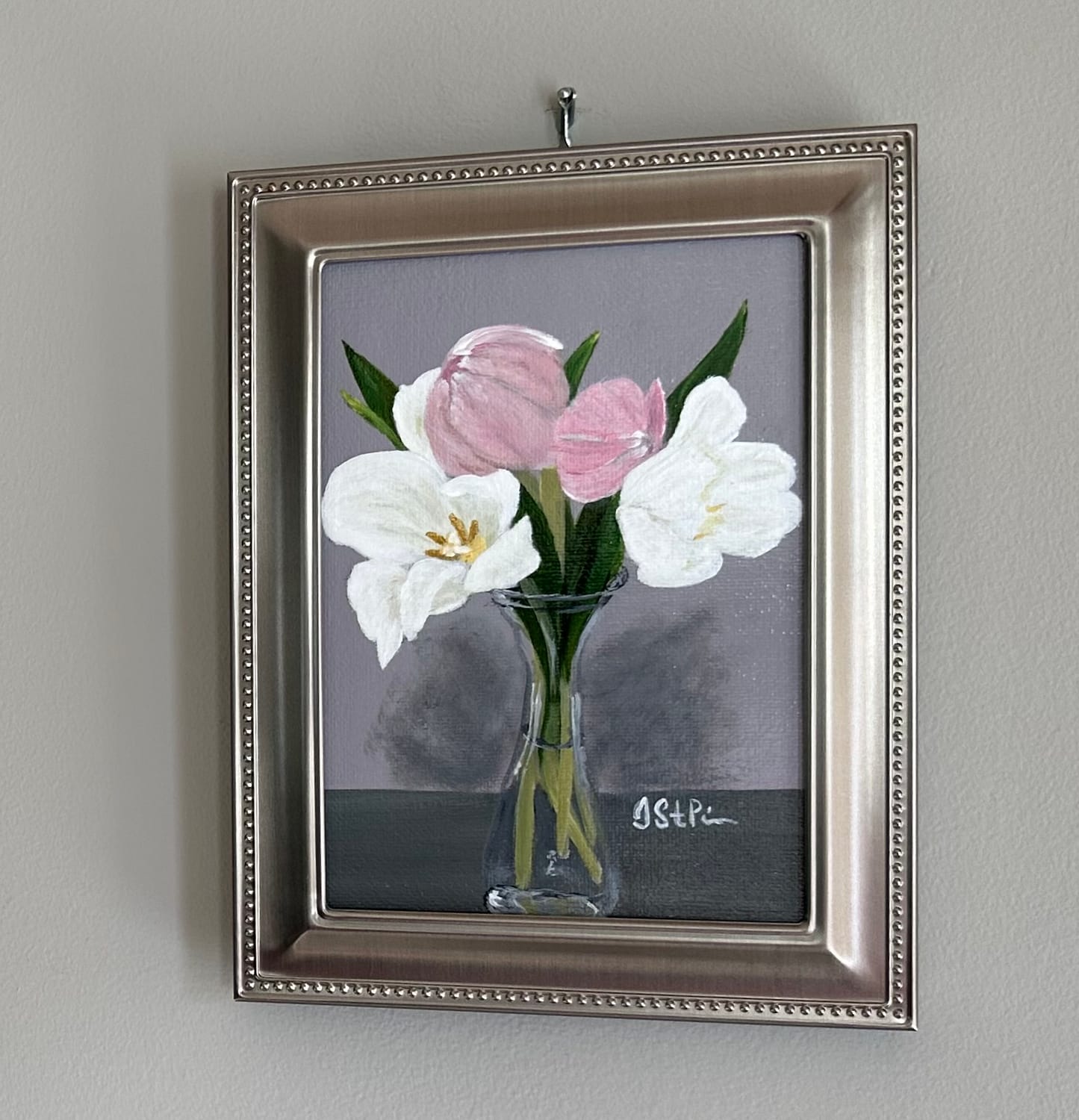A small painting of pink and white tulips in a clear carafe