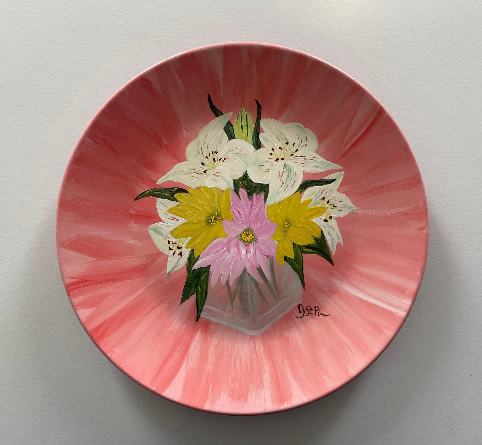 Photo of a pink hand painted plate with white lilies and pink and yellow daisies in a glass vase