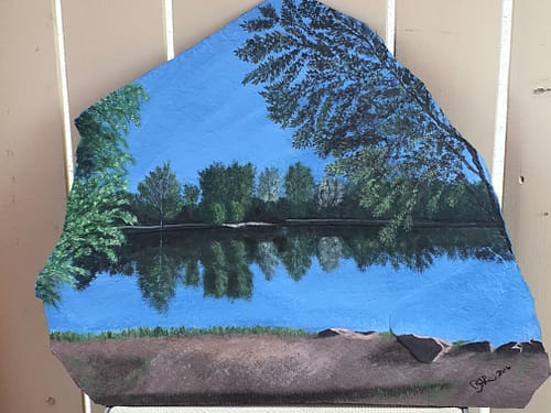 A pond scene painted on a large piece of slate rock