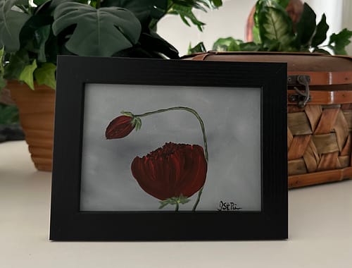 A painting of red poppies on a grey background in a black frame