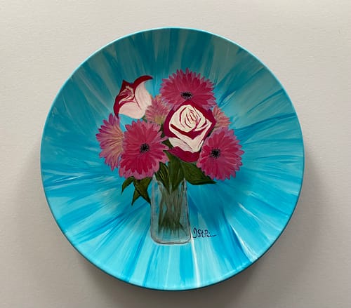 Photo of a Turquoise plate hand painted with Pink Roses and Gerbera Daisies in a glass vase