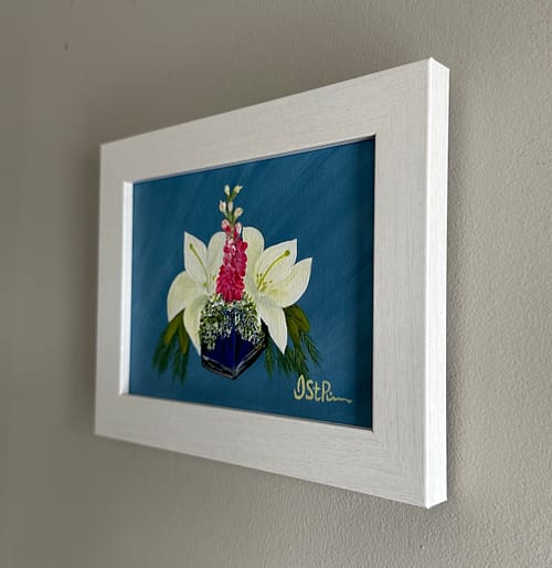 A painting of white lilies in a blue glass vase in a white frame