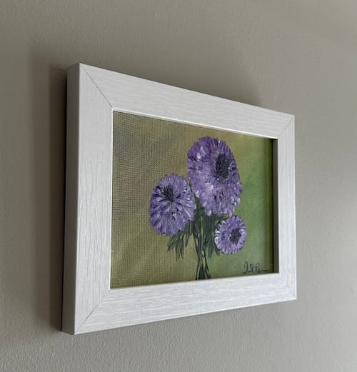 A painting of purple Chrysanthemums on a green background and in a white frame