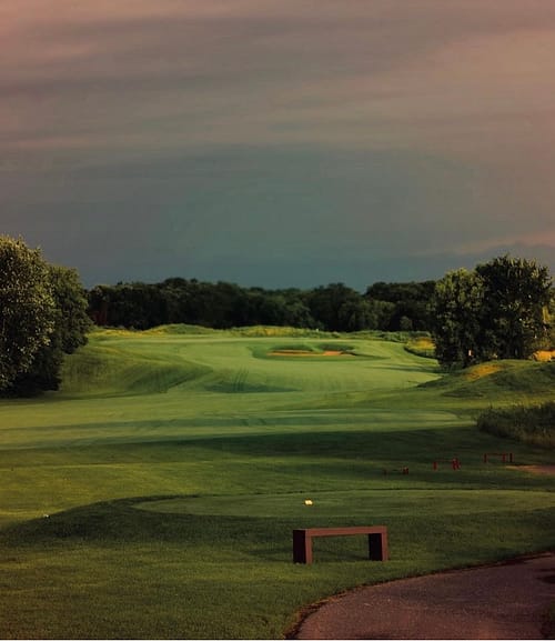 Photo of a golf course green with a pink clouds overhead